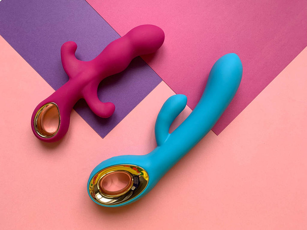 Sex toys. Pink and blue vibrators on a pink background.  - Фото, изображение