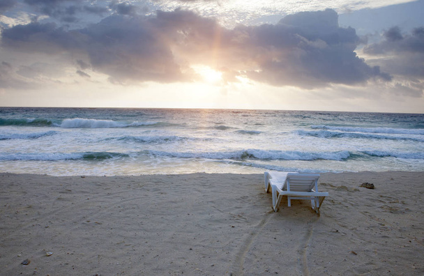 cadeira da plataforma na praia arenosa do mar com ondas no sunris adiantado da manhã
 - Foto, Imagem