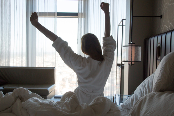 Beweglichkeit des Oberkörpers, schöne junge Frau streckt sich nach dem Aufwachen auf dem Bett - Foto, Bild