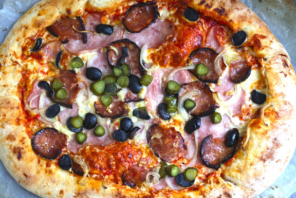 kulatá horká pizza s bzučením, klobásou, okurkou, olivovou cibulí a che - Fotografie, Obrázek