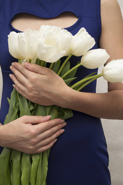 Prezent dla dziewczynki na Dzień Kobiet, Dzień Matki, Walentynki. Kobieta trzyma w rękach bukiet białych tulipanów. Kartka z tulipanami. - Zdjęcie, obraz