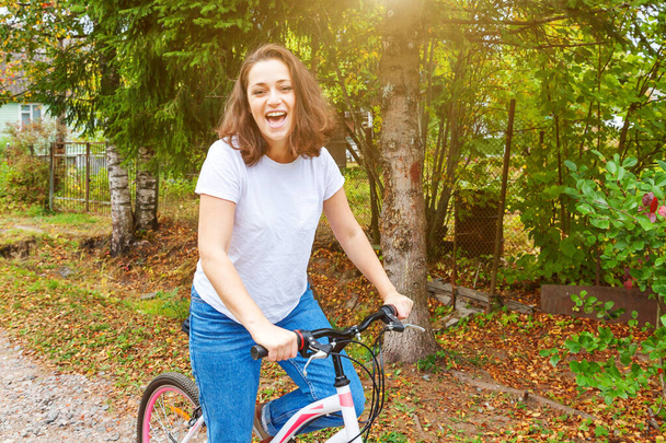 Νεαρή γυναίκα ιππεύει ποδήλατο στο πάρκο της πόλης το καλοκαίρι. Ενεργό  - Φωτογραφία, εικόνα