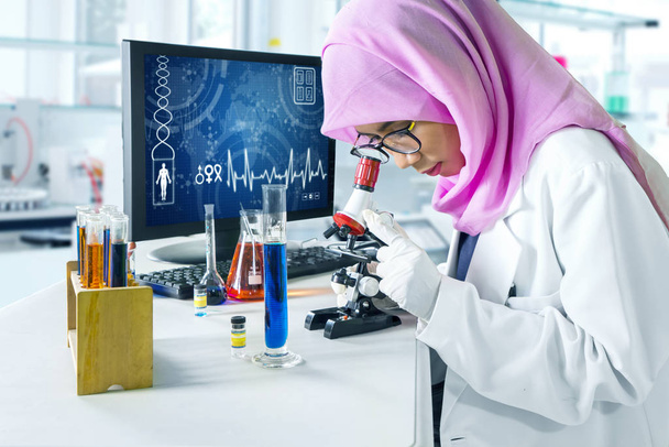 Muslim scientist looking through microscope - Foto, imagen
