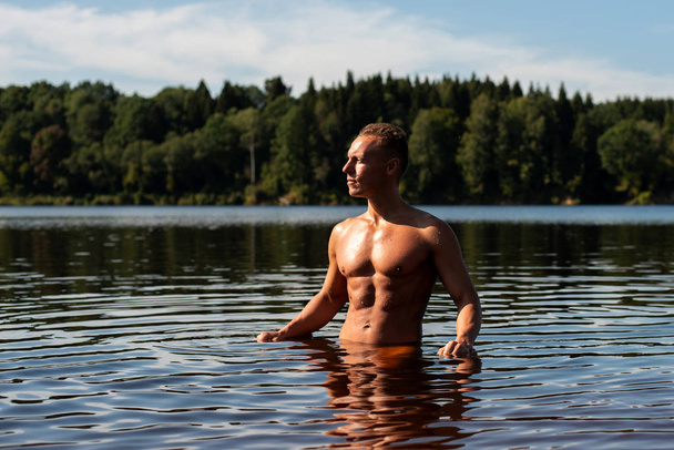 A beautiful muscular man on a lake in the water. - 写真・画像