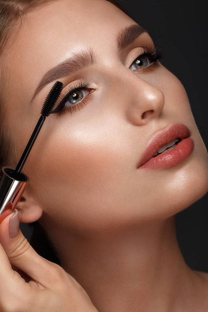 Beautiful girl with sexy lips and classic makeup with cosmetic mascara brush in hand. Beauty face. - Foto, Imagem