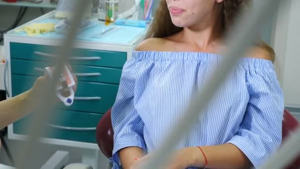 Odontología infantil. Concepto de protección dental. Linda chica de 16 años con modelo de dientes en las manos. Sonriente paciente alegre en el consultorio del dentista. Disparo en 4k
 - Imágenes, Vídeo