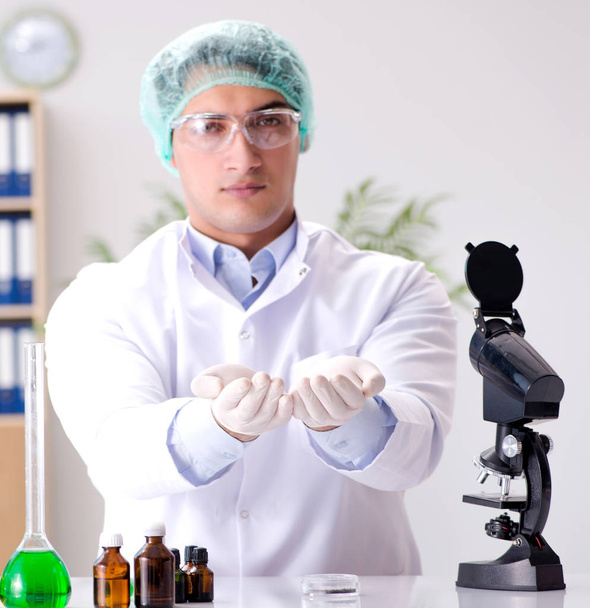 Молодой врач работает в лаборатории с микроскопом
 - Фото, изображение