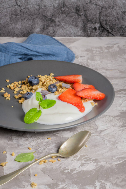 Ripe blueberries and strawberries with yogurt and granola - Foto, afbeelding