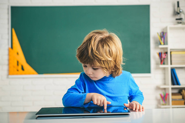Grundschule und Bildung. Kleiner Junge spielt mit digitalem Tablet. Schüler mit digitalem Tablet im Klassenzimmer. - Foto, Bild