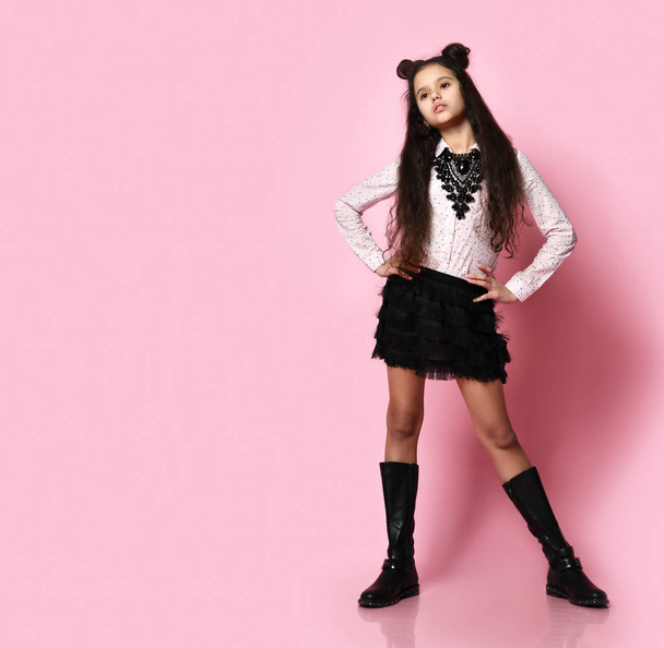 Young girl in stylish clothing and accessories posing over pink background - 写真・画像