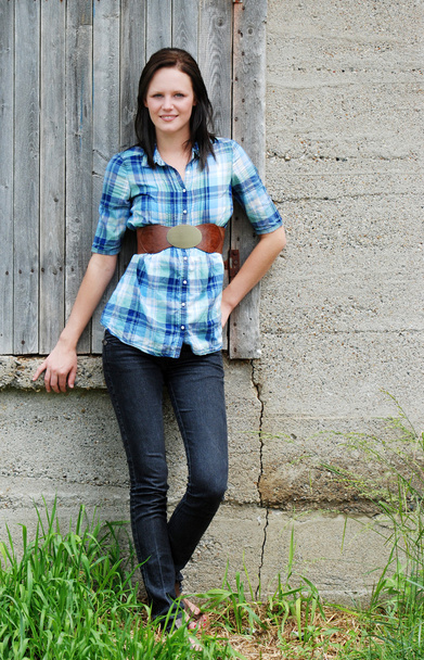 Young woman leaning on barn - Φωτογραφία, εικόνα