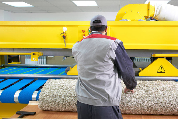 Trabajador de lavandería en el proceso de trabajo en la máquina automática para el lavado de alfombras en la limpieza en seco
 - Foto, Imagen