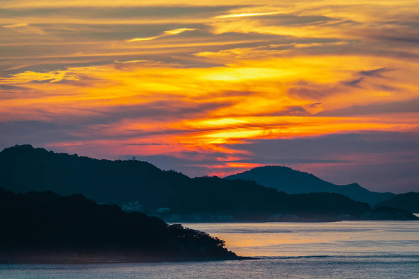 カラフルな光の背景に夕日とシルエットの島p - 写真・画像