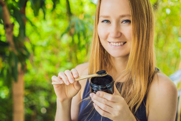 Young woman brush teeth using Activated charcoal powder for brushing and whitening teeth. Bamboo eco brush - Foto, immagini