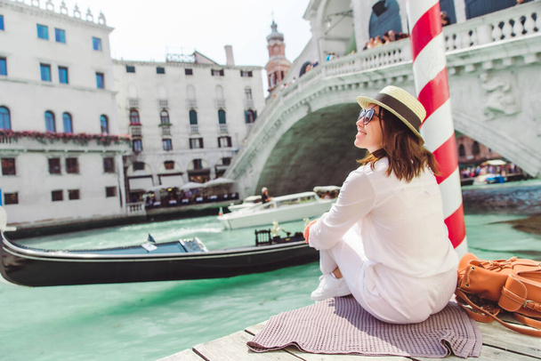 mujer sentada cerca de puente de rialto en Venecia mirando a Gran Canal con góndolas
 - Foto, Imagen
