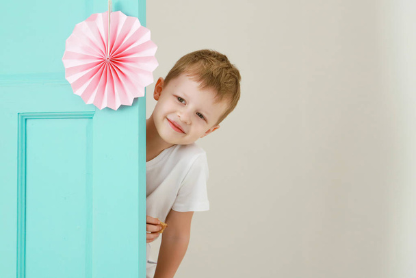 Šťastný malý rozkošný chlapec vykoukne ze dveří domů. Dětství, zábava a lidé koncept. - Fotografie, Obrázek