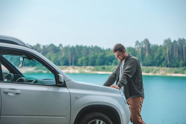 samochód podróży koncepcja mężczyzna patrząc na mężczyznę na SUV samochód kaptur jezioro na tle - Zdjęcie, obraz