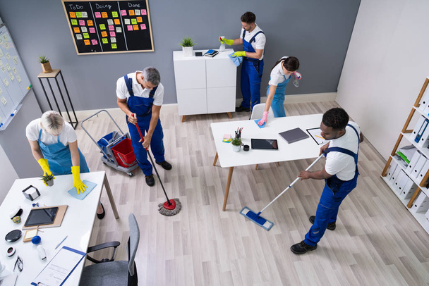 Group Of Janitors In Uniform Cleaning The Office With Cleaning Equipment - Zdjęcie, obraz