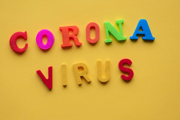 Cornona virus gespeld tegen een gele achtergrond - Foto, afbeelding
