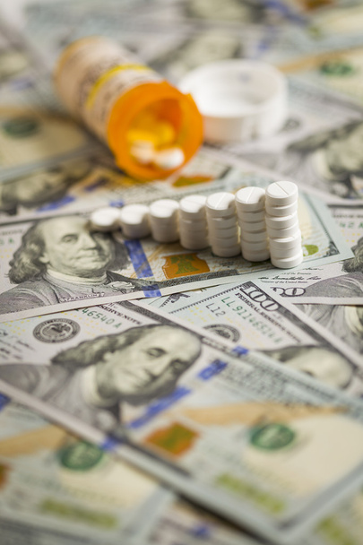 Χάπια φαρμάκων στοιβαγμένα στο πρόσφατα σχεδιασμένο εκατοδόλαρο νομοσχέδιο - Φωτογραφία, εικόνα