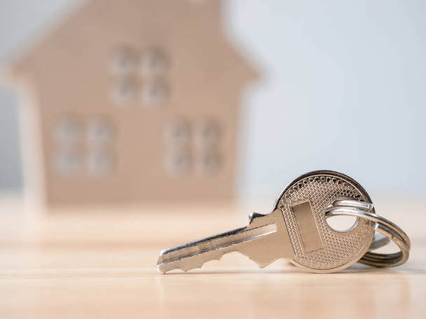 Ключ будинку з дерев'яним домашнім тлом розмитий, нерухомість і нерухомість інвестиції та іпотечна фінансова концепція будинку
 - Фото, зображення