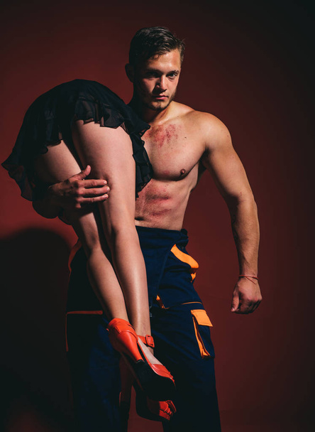 Firefighter sexy body muscle man holding saved sexy woman. Intimate relationship and sexual relations. Hot sexy Firefighter. Superhero. Passion and sensual touch. - Foto, imagen