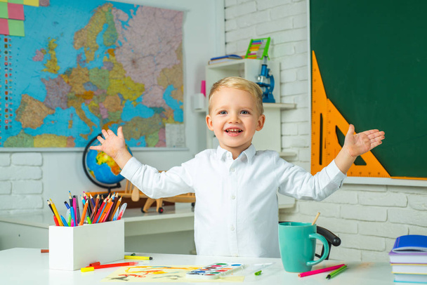 Schoolkid or preschooler learn. Little student boy happy with an excellent mark. School interiors. Kid is learning in class on background of blackboard. - Fotó, kép