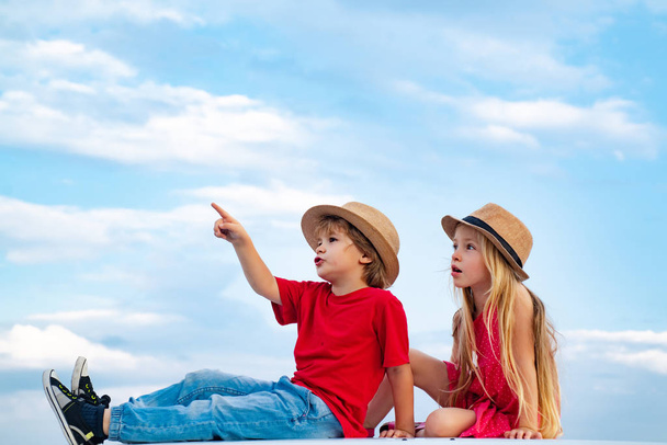 Funny little girl and boy. Happy children in summer on blue sky background isolated. Happy brother and sister. Children playing. Childhood friends Children enjoy life and nature. - Foto, imagen