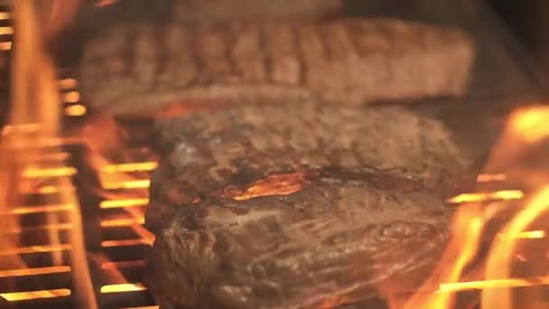 meat on the grill. juicy pieces of meat with beautiful stripes are fried on a hot grill on an open flame with sparks. BBQ. Pork or beef cooked on the grill. Barbecue outside the house. - Footage, Video