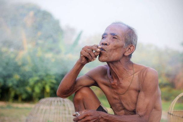 Yaşlı Asyalı erkekler sigara içiyor.. - Fotoğraf, Görsel