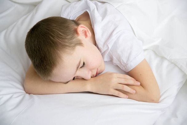 Cute boy sleeps in a bed on a white bed. View from above. - 写真・画像