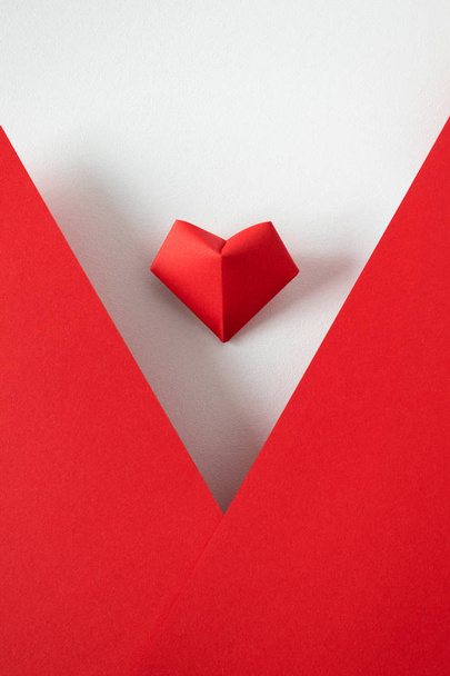 origami corazón sobre fondo blanco y marco de papel rojo, vista superior
. - Foto, imagen