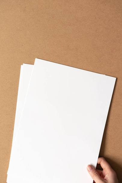Рука держать белые чистые чистые листы бумаги на картонном фоне
 - Фото, изображение