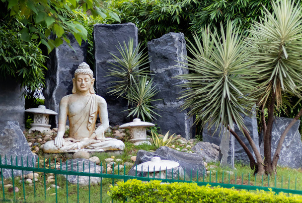 Önünde yeşil korkuluklar olan Buda heykelinin önü. - Fotoğraf, Görsel
