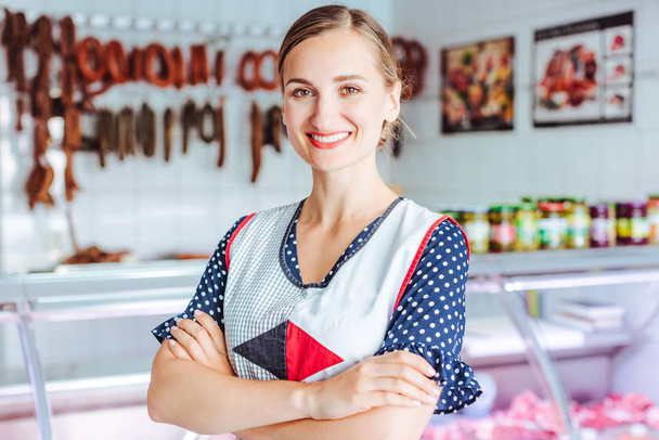 Mulher orgulhosa vendendo carne e salsichas no açougue
 - Foto, Imagem