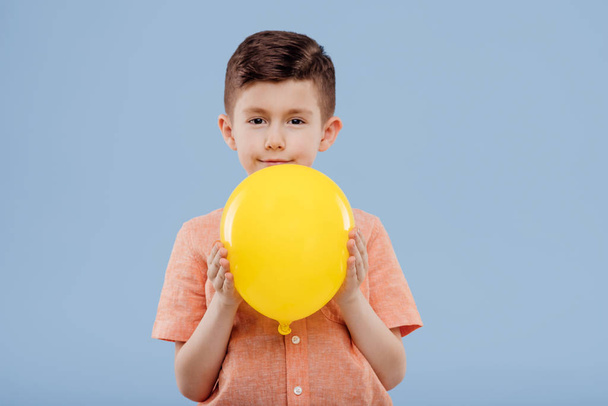 little boy with yellow balloon. looks at the camera, - Foto, Bild