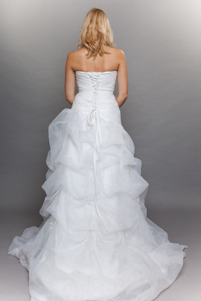 blonde bride white long wedding dress back view on gray - Fotó, kép