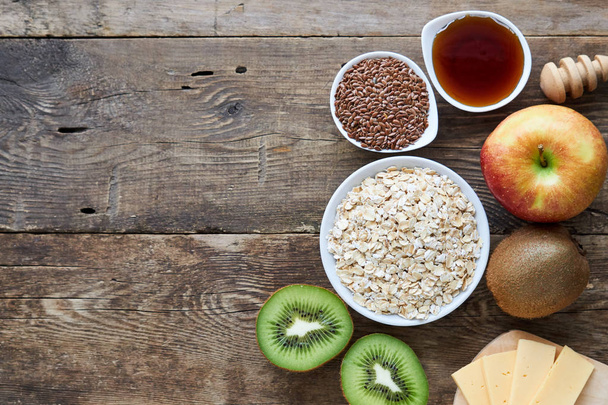 Ingredients for cooking oatmeal porridge with fruit on a wooden background                                - Fotoğraf, Görsel