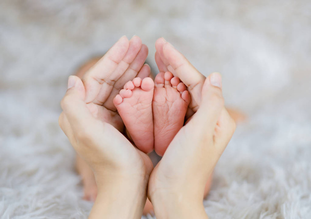 Mom holding in the hands feet of newborn baby. - Fotoğraf, Görsel
