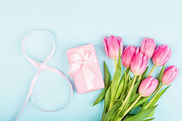 View from above tulips and gift box with copy space on blue. Background for womens day, 8 March Valentines day, 14 february. Flat lay style, top view, mockup, template, overhead. Greeting card - 写真・画像