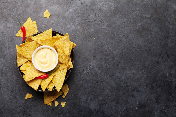 Mexican nachos chips with cheese sauce. Top view flat lay on stone table with copy space - Photo, Image