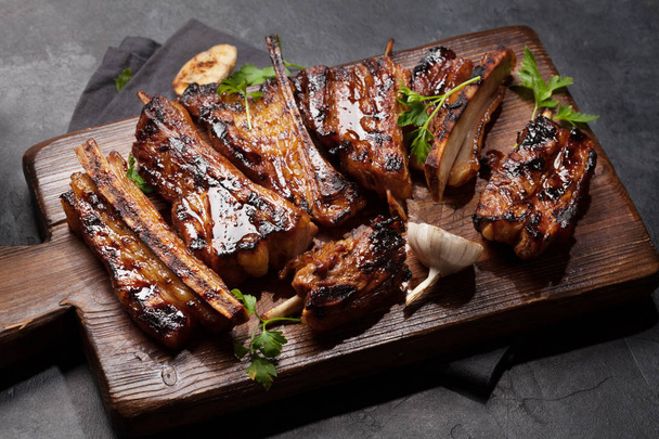 Barbecue rundvlees ribbetjes met bbq saus gesneden op een houten plank - Foto, afbeelding