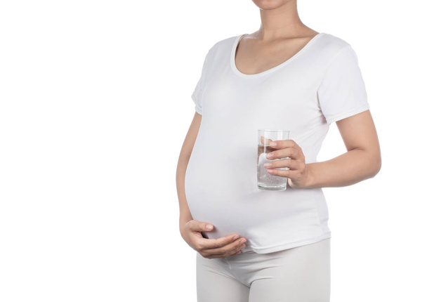 pregnant woman holding a glass of water isolated on a white back - Photo, Image