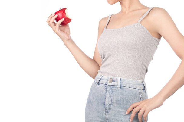 mulher em top tanque cinza e jeans comendo uma maçã vermelha isolada o
 - Foto, Imagem