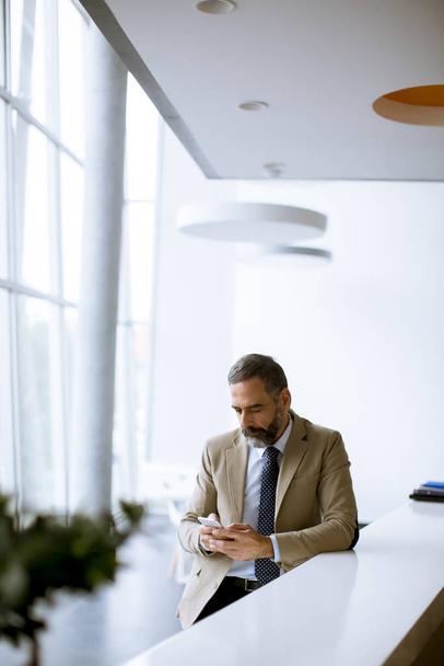 Homme d'affaires séduisant utilisant le téléphone portable dans un bureau moderne
 - Photo, image