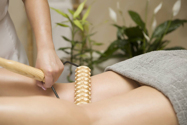 Zbliżenie maderoterapii masażem nóg antycellulitowym z drewnianym wałkiem do masażu - Zdjęcie, obraz