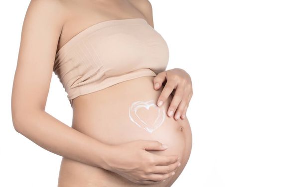 έγκυος γυναίκα τρίψιμο κρέμα στην κοιλιά της απομονώνονται σε λευκό backg - Φωτογραφία, εικόνα