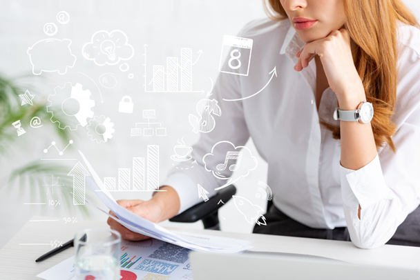 Обрезанный взгляд бизнесвумен, держащих досье рядом с графиками и ноутбуками на столе, бизнес-иллюстрация
 - Фото, изображение