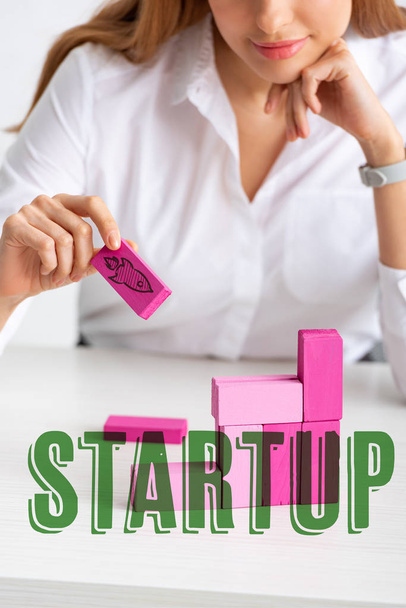 Selective focus of businesswoman stacking marketing pyramid with pink building blocks isolated on grey, startup illustration - Foto, immagini