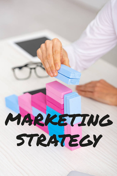 Przycięty widok businesswoman podejmowania piramidy marketingowej z kolorowych budulców na stole, strategii marketingowej ilustracji - Zdjęcie, obraz